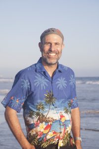 K’vod wearing a Hawaiian shirt on a beach in California